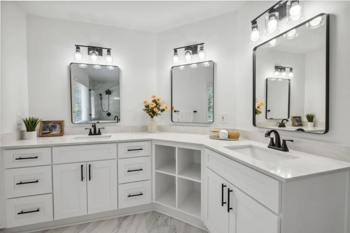 A bright and modern bathroom with a white double vanity, black-framed mirrors, and contemporary lighting.