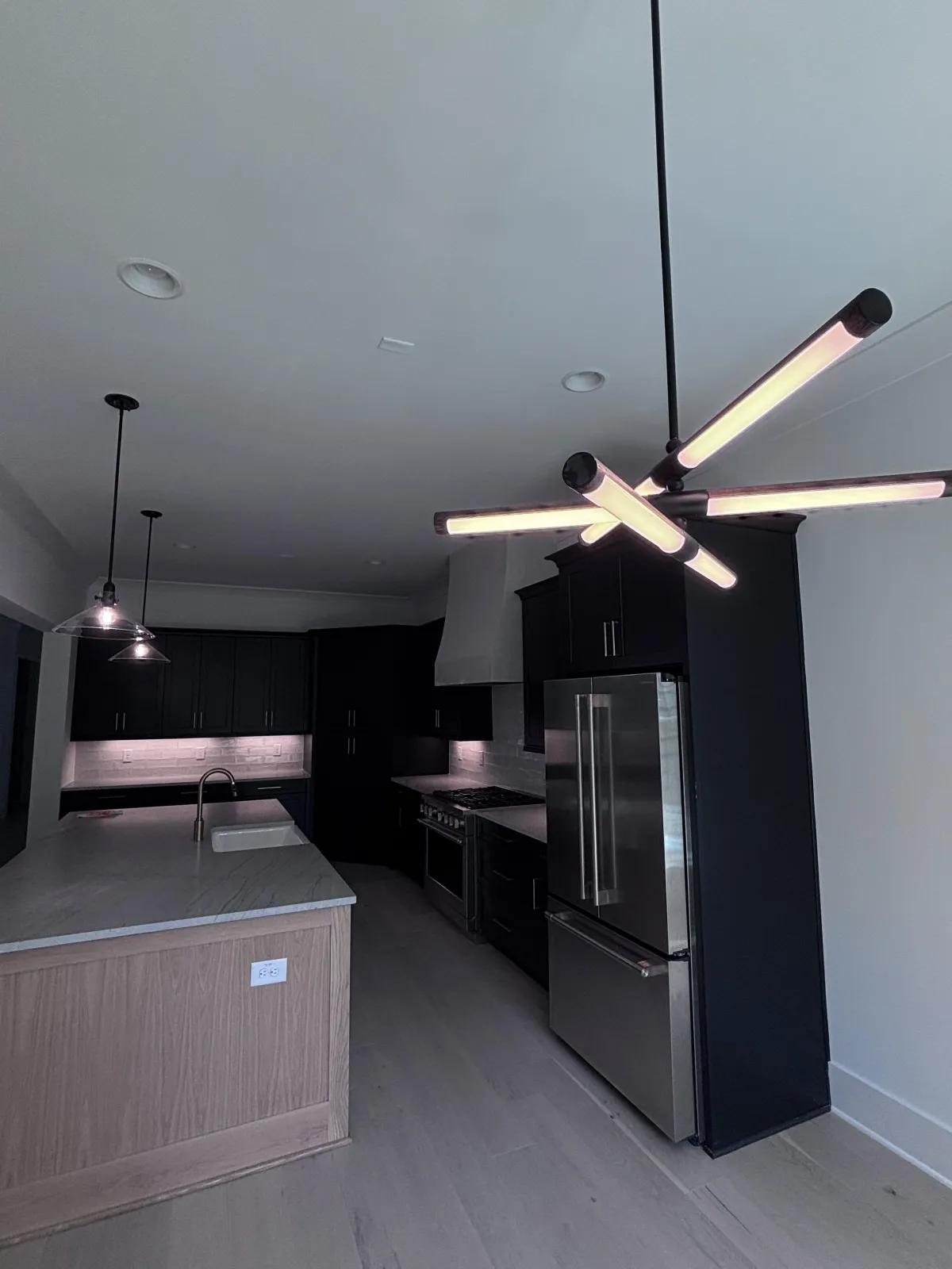 Sleek, modern kitchen featuring dark, professionally painted cabinets and a contemporary light fixture.