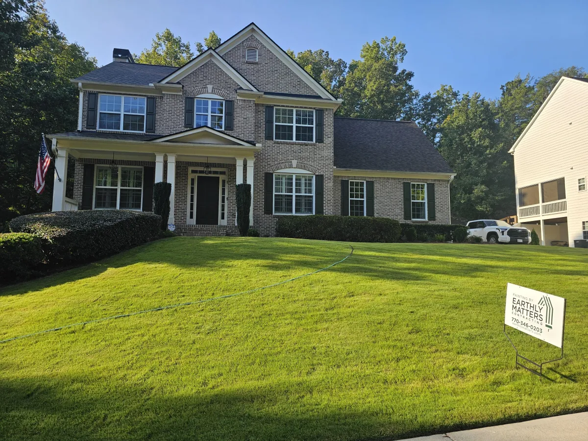 The same home looking crisp and clean after a fresh coat of paint, with an Earthly Matters sign proudly displayed in the green lawn.