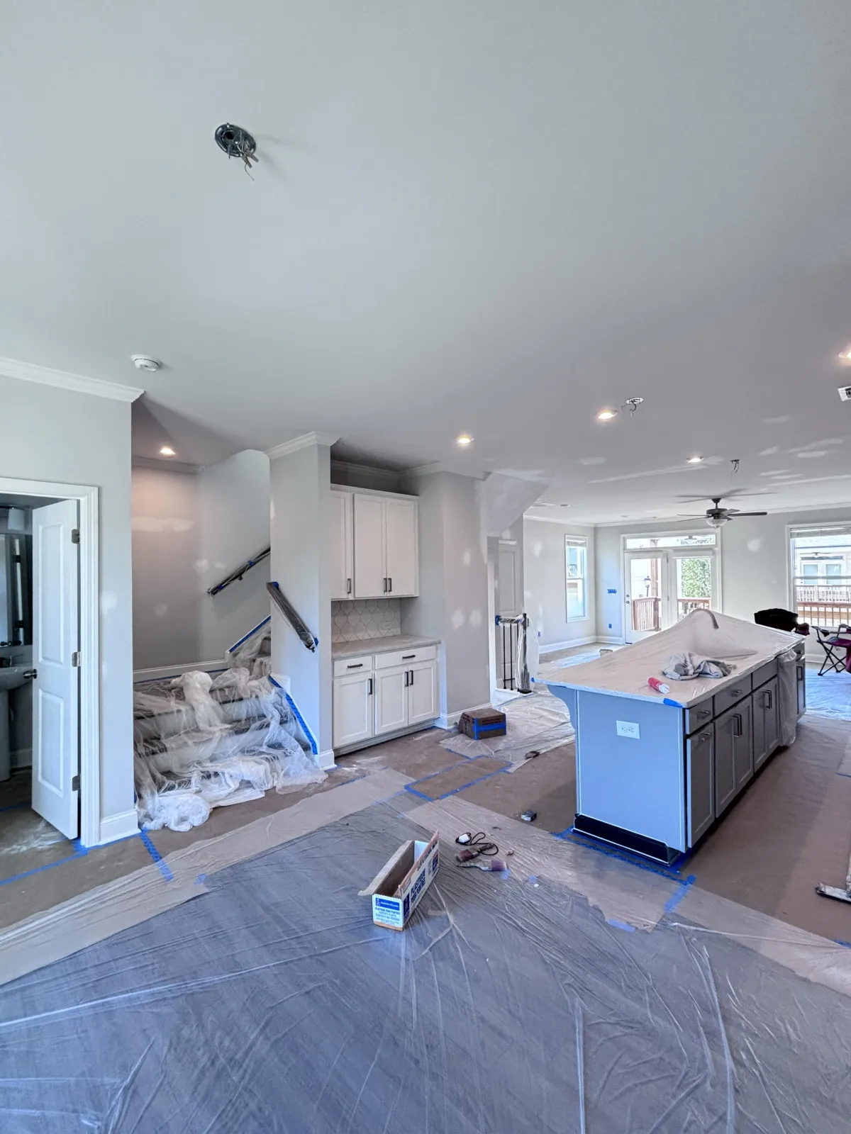 A white kitchen being professionally prepped for painting with a plastic coverings in a controlled environment for a flawless, factory-like result.