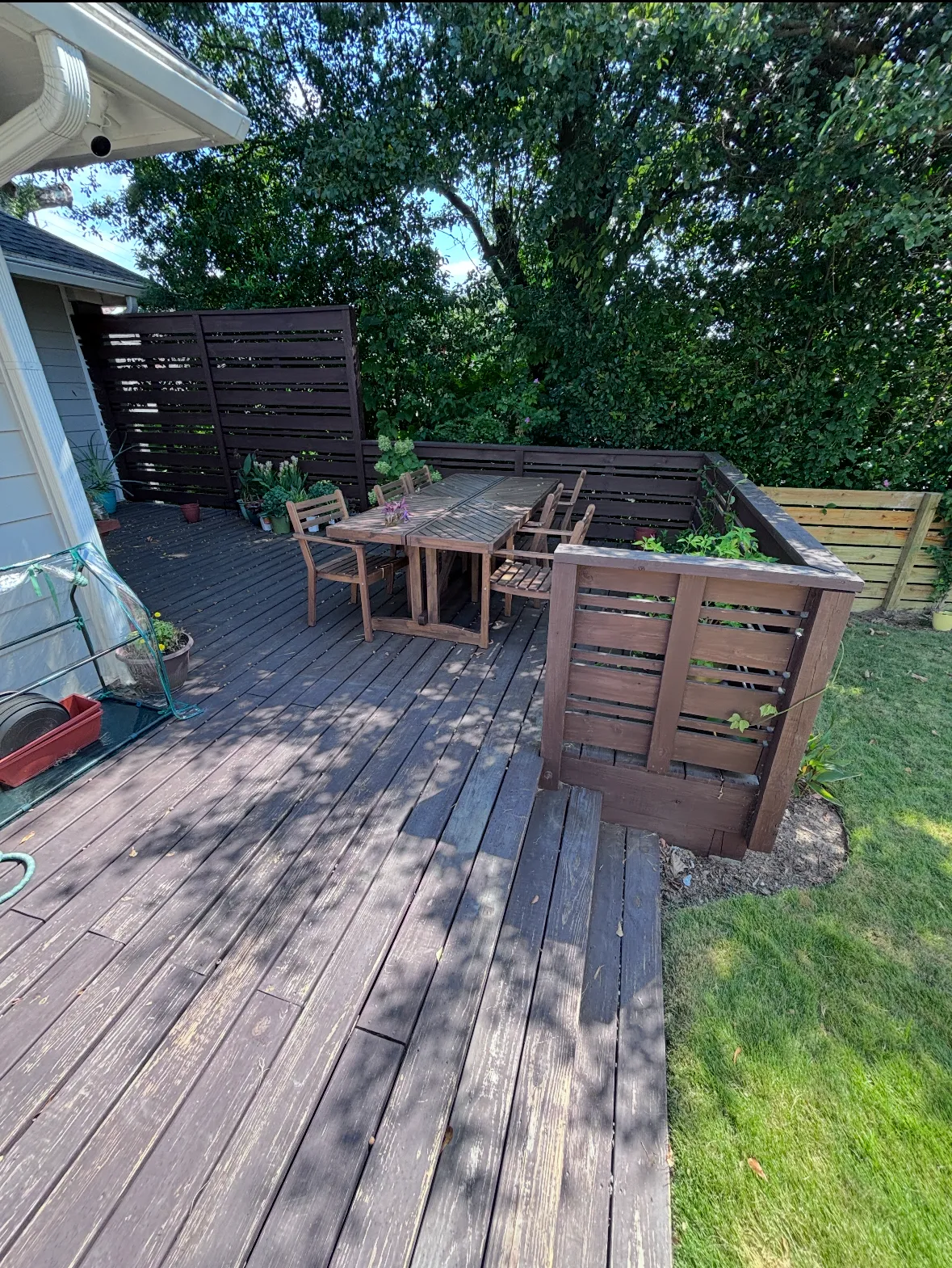A worn, faded wooden deck and privacy screen showing significant weather damage before restoration.