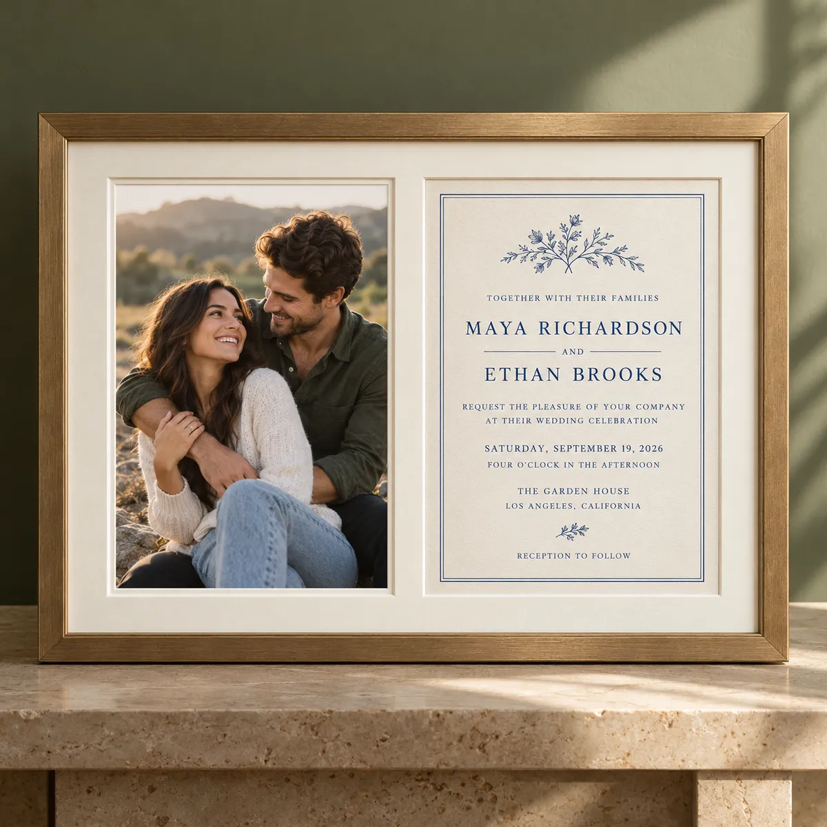 Engagement photo of a couple displayed beside an elegant wedding invitation in a custom walnut frame with cream double matting.