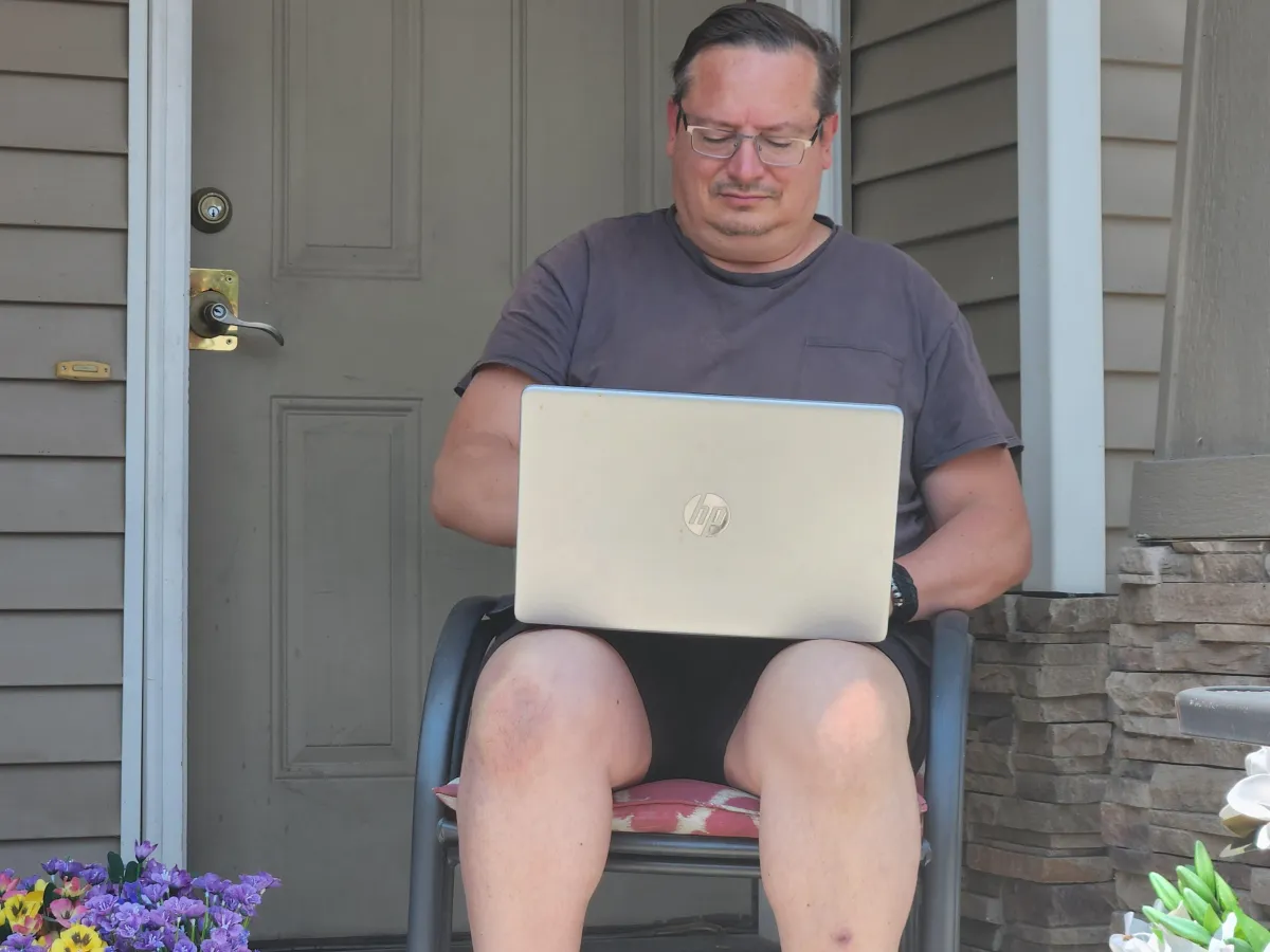 Michael in front of home on laptop