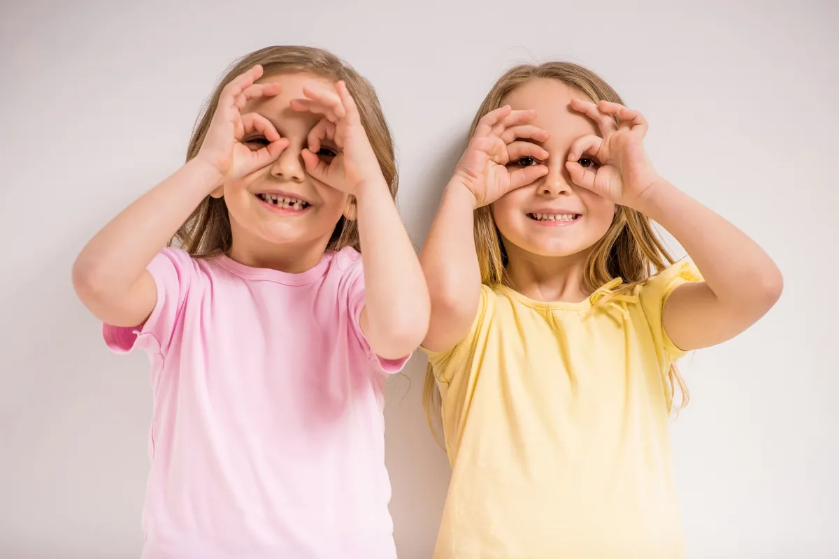 Two happy girls making playful circle shapes with hands over eyes