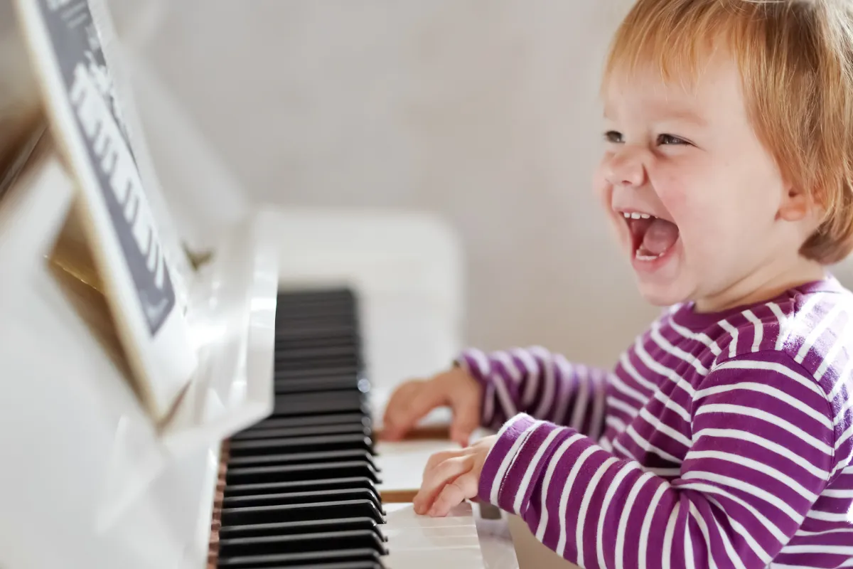 Smiling child playing piano during music lesson