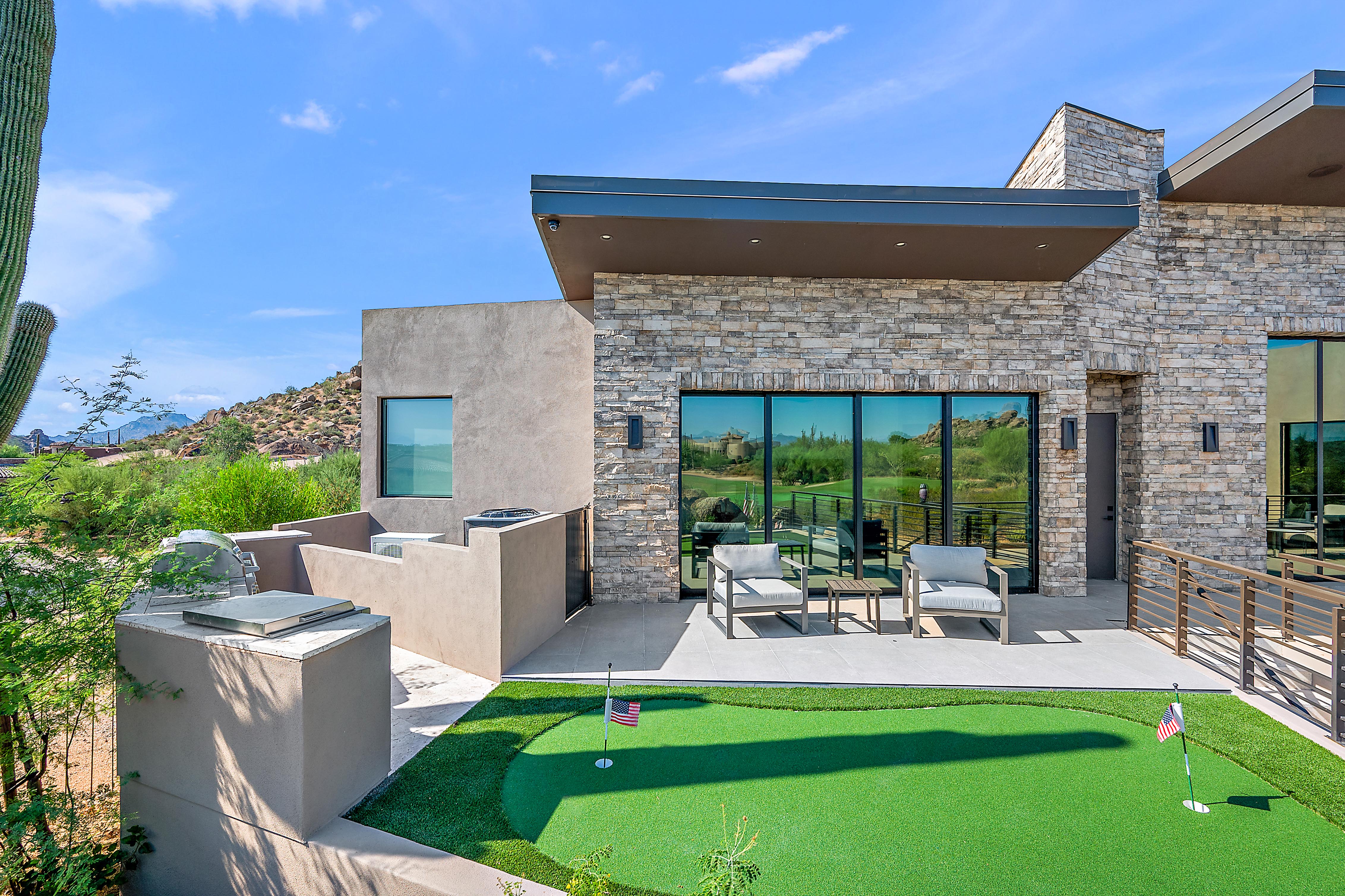 Full luxury home exterior renovation with custom pool, spa, desert landscaping, stone columns, and floor-to-ceiling indoor-outdoor connection — N&M Home Services, Arcadia and Desert Mountain AZ