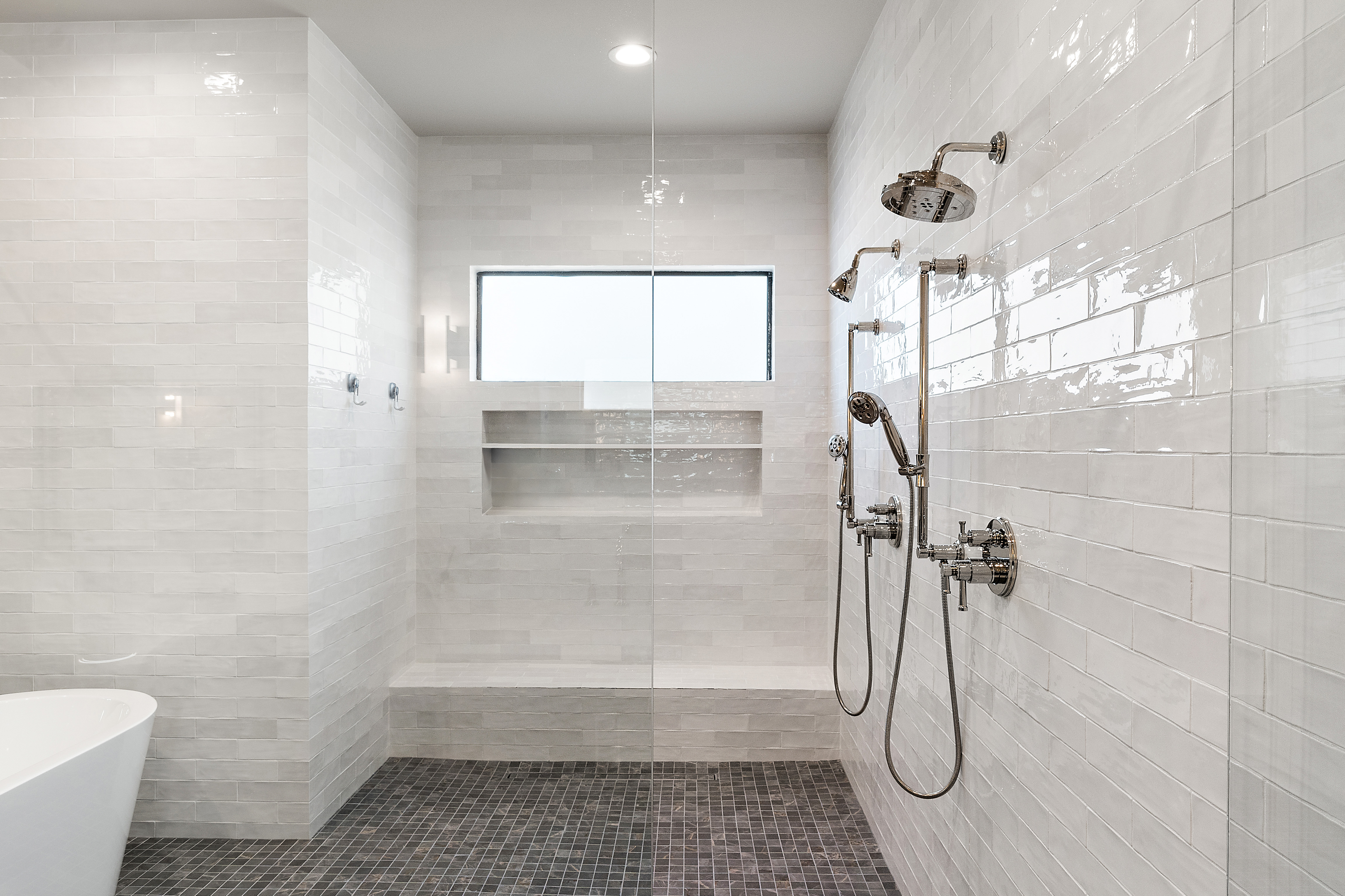 Oversized walk-in shower with dual shower fixtures, glossy subway tile, and frameless glass door — N&M Home Services, Paradise Valley AZ