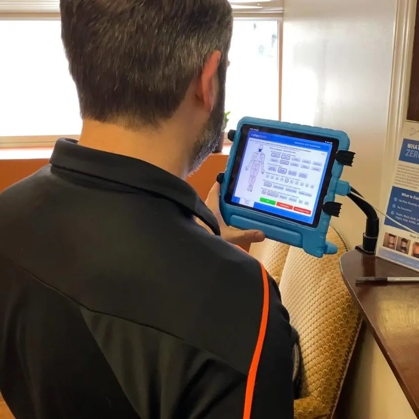 Patient completing a digital posture and pain assessment before chiropractic treatment.