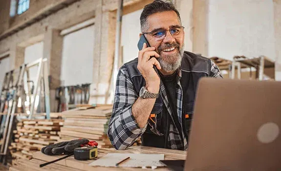 Local contractor in Longview, TX answering a call at his workshop desk, representing done-for-you marketing support