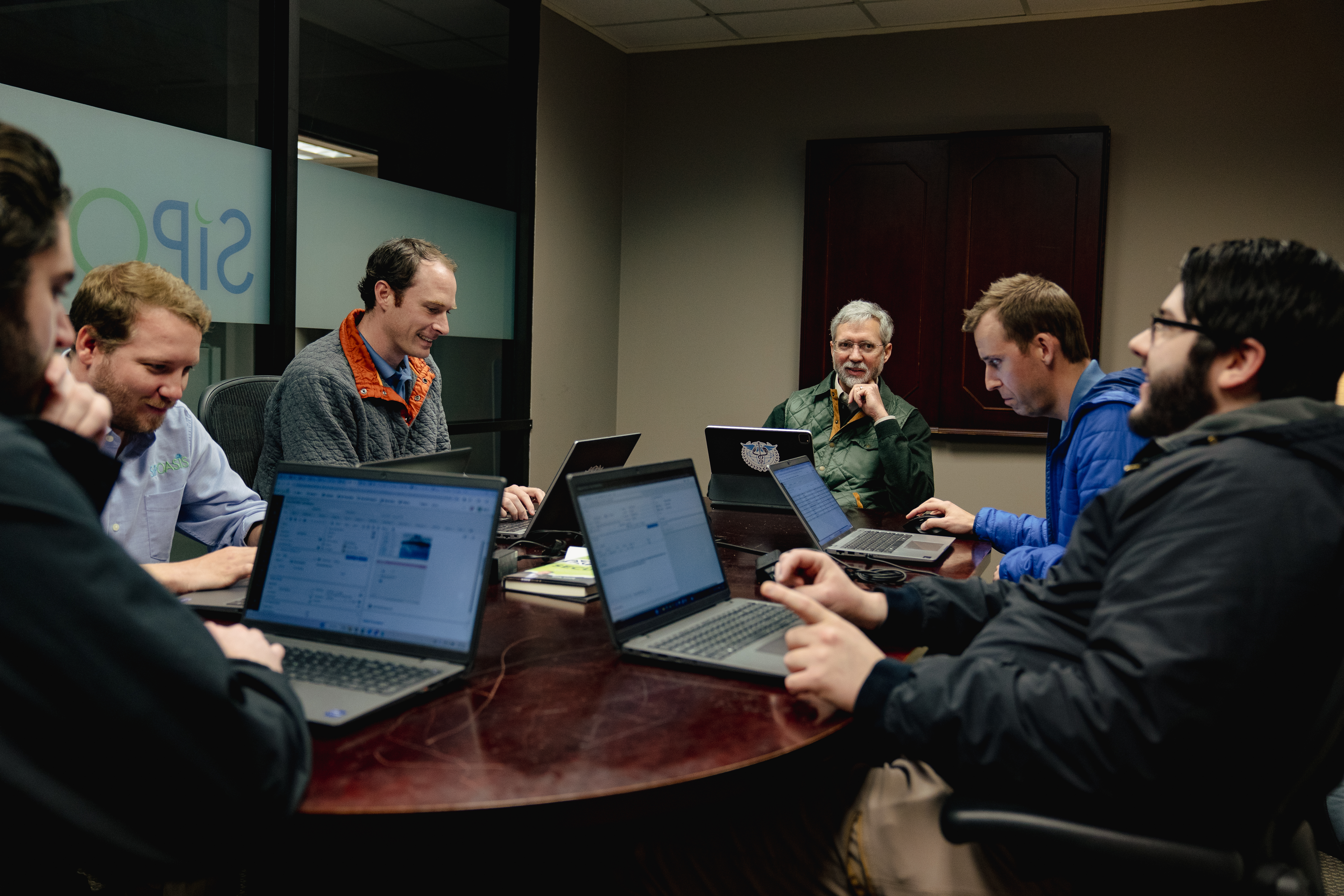 Smiling team collaborating around a laptop in a modern office