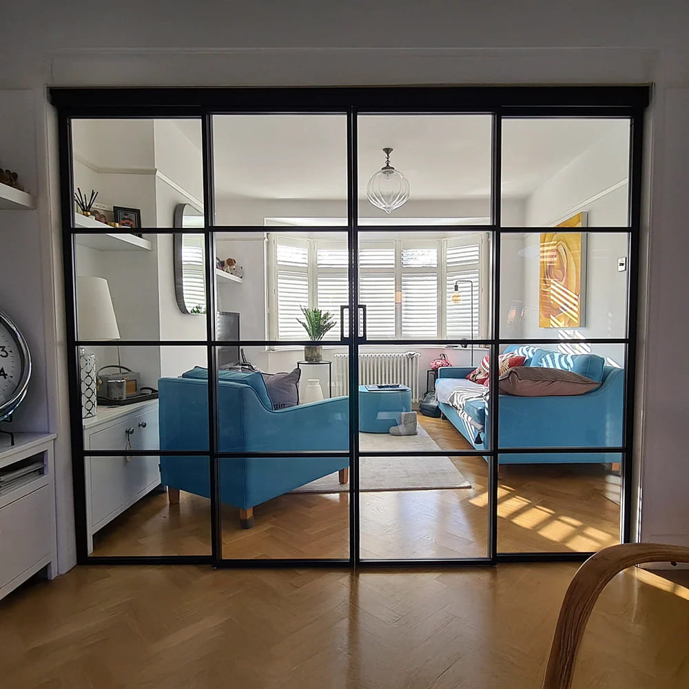 Black-framed glass partition with double hinged doors and fixed sidelights in a modern home. | Creoglass