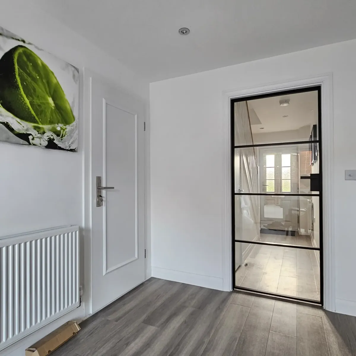 Modern industrial-style single hinged internal door, known as Crittall-style, separating a white hallway from a staircase, enhancing light flow. | Creoglass