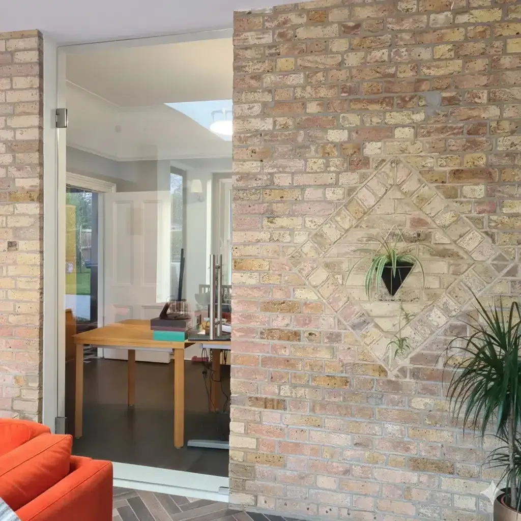 Single hinged glass door and fixed panel in a black frame next to an interior brick wall. | Creoglass