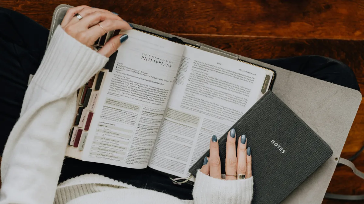 Open Bible and notebook on a person’s lap, representing biblical guidance on money, stewardship, debt, and giving.