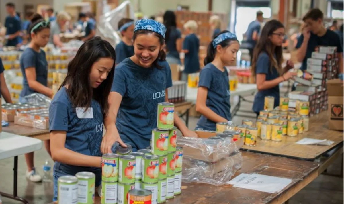 Grupo de voluntárias jovens organizando doações de alimentos e cestas básicas em evento comunitário de ONG