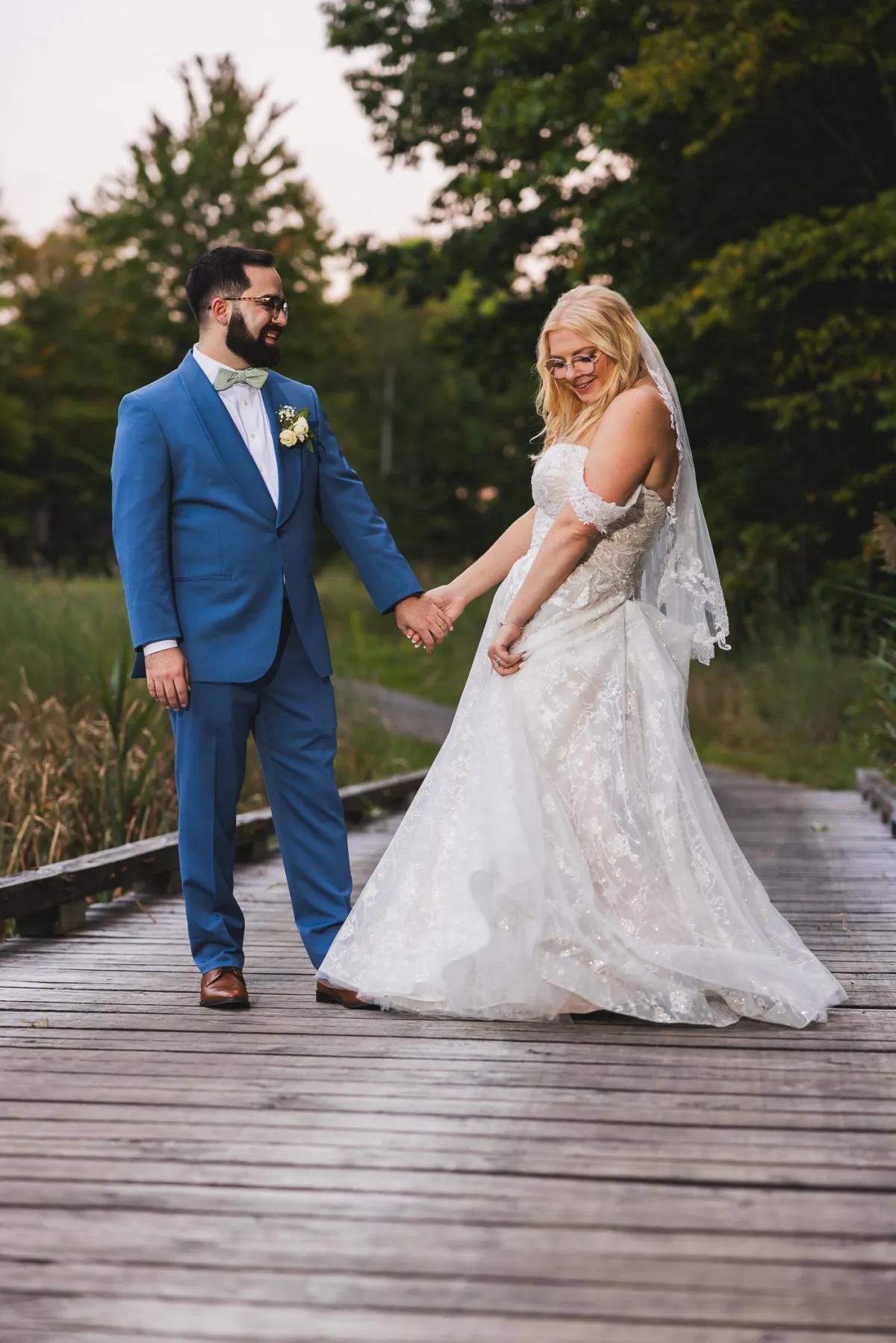 Bride and groom dancing on a golf course bridge at sunset.