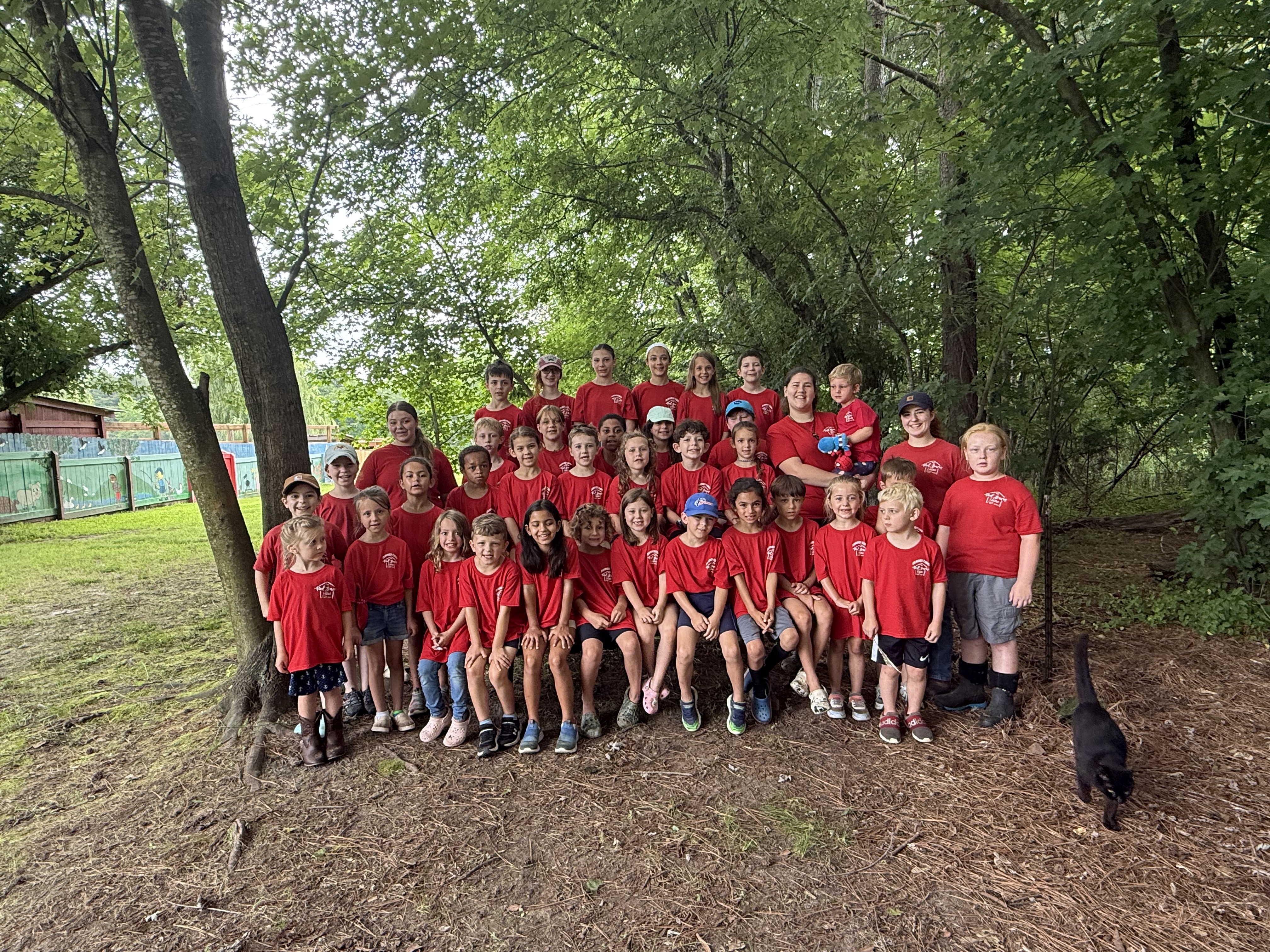 Counselor and kids walking through a sunny farm field at Red Barn Camp
