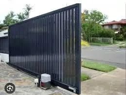 A driveway entrance with a sliding white ornamental gate