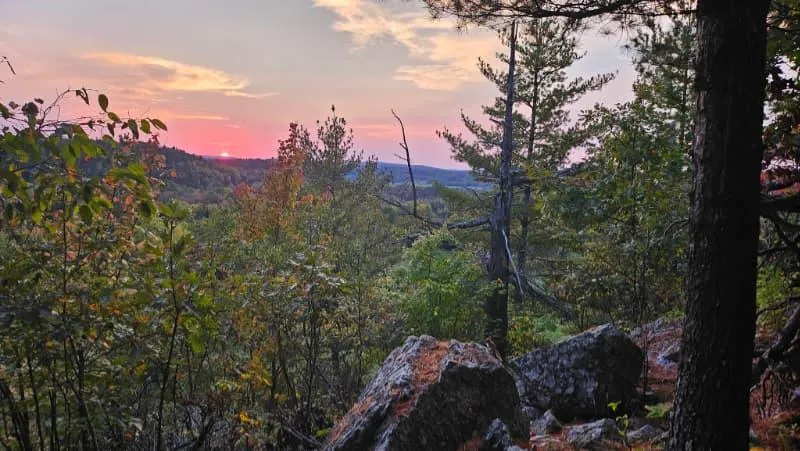 Sunset view from Cliffside Camp at The Ark in Quebec’s Outaouais region, surrounded by forest and rocky cliffs.