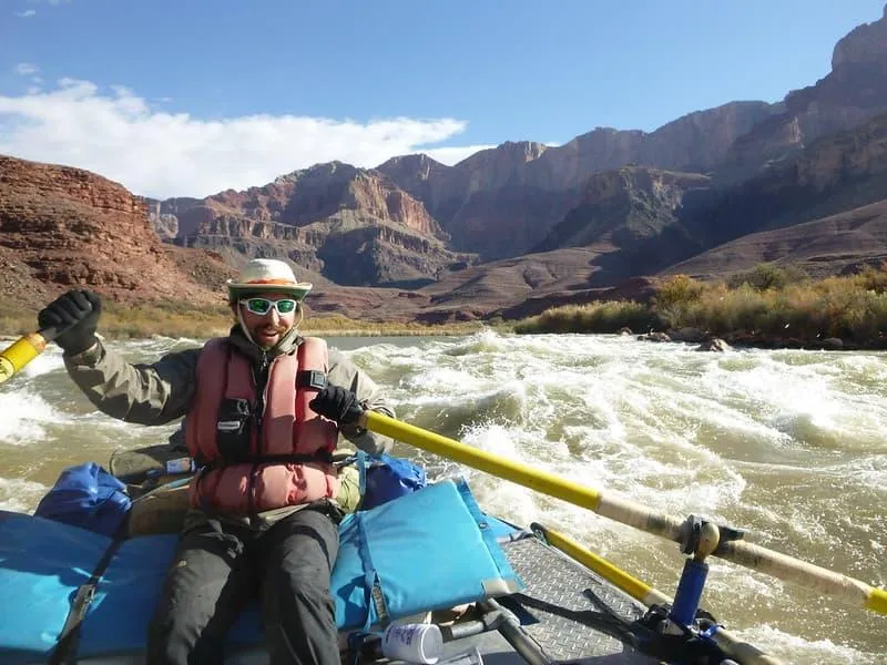 Mike Caldwell guiding a raft through whitewater rapids in the Grand Canyon, part of his experience as an international rafting guide.