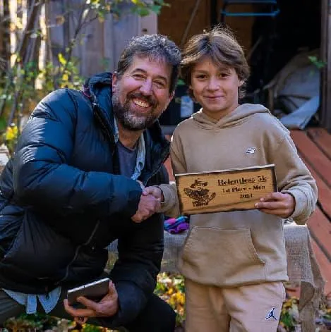 Young runner receiving a custom cedar award plaque at the Mad Trapper Racing series in Quebec