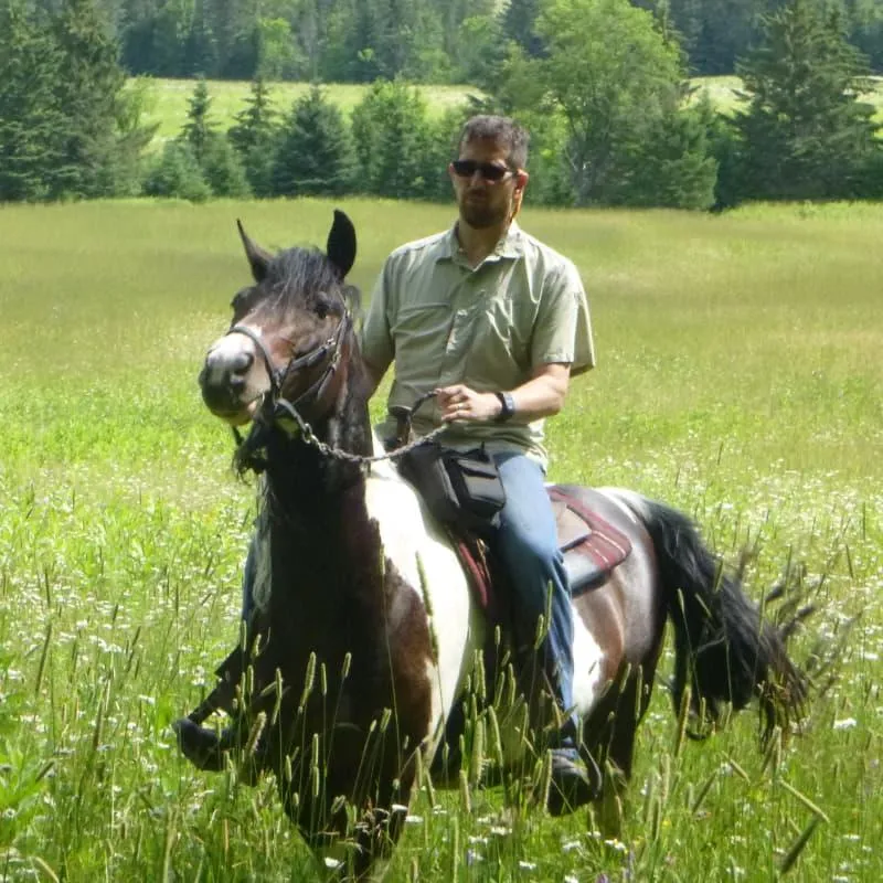 Mike Caldwell, founder of The Off Grid Ark, riding his horse through a field at his 164-acre off-grid property in Western Quebec.