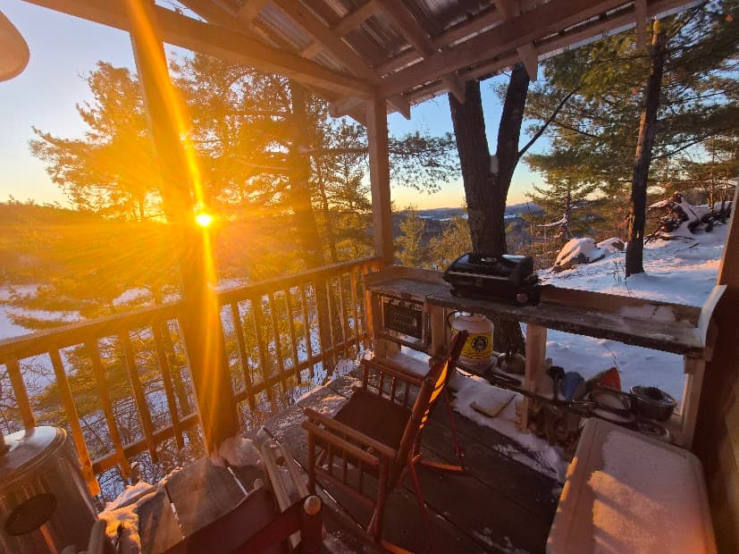 Winter sunset view from Cliffside Camp at The Ark in Quebec’s Outaouais region, surrounded by forest and rocky cliffs.