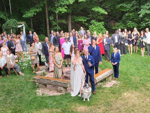 Wedding couple standing with guests gathered outdoors for a group photo