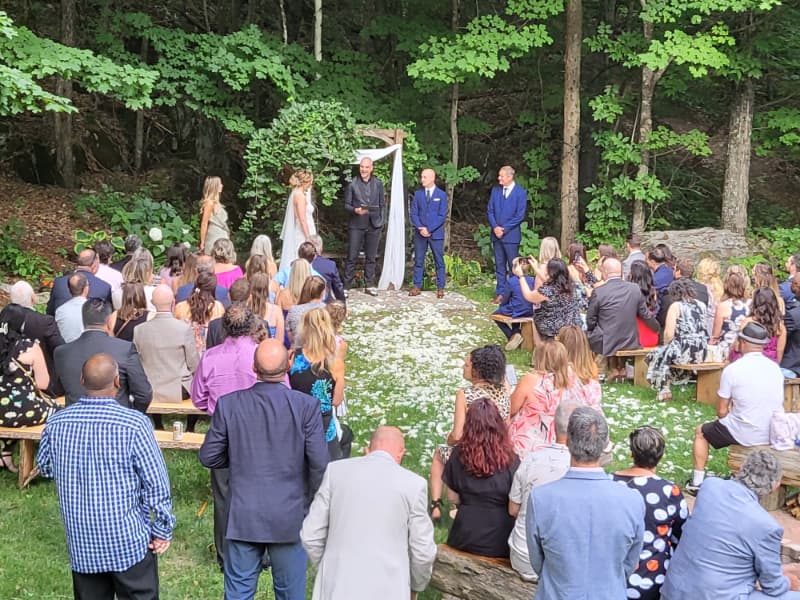 Guests gathered for an outdoor forest wedding ceremony at The Off Grid Ark near Ottawa–Gatineau, with the couple standing at the arbor surrounded by trees.