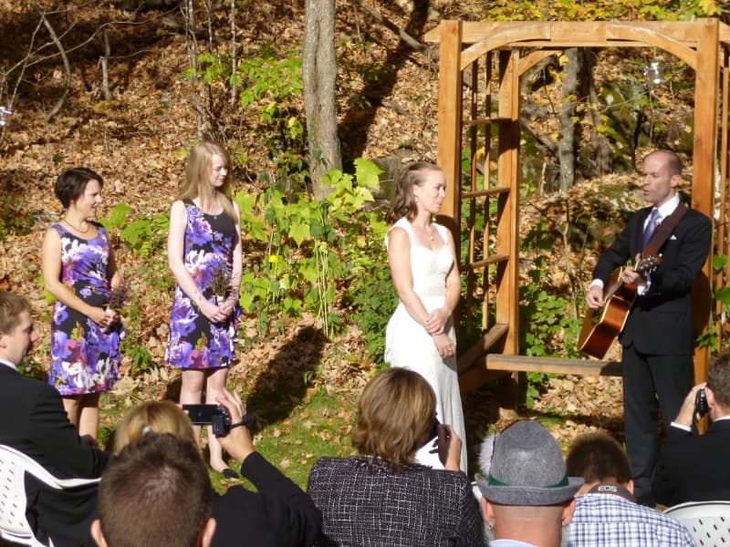 Personalized outdoor wedding ceremony at The Off Grid Ark near Ottawa–Gatineau, with the groom playing guitar during the vows in a forest setting.