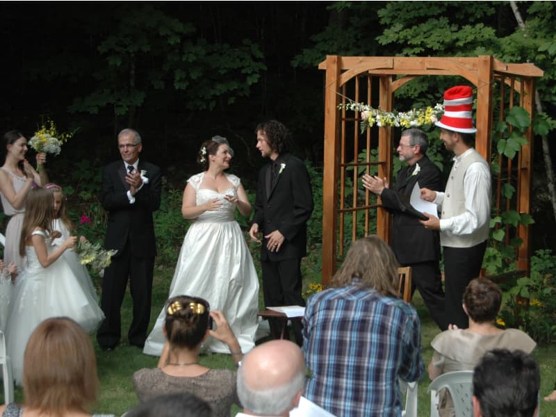 Personalized outdoor wedding ceremony at The Off Grid Ark near Ottawa–Gatineau, with the officiant wearing a Dr. Seuss hat during the vows in a forest setting