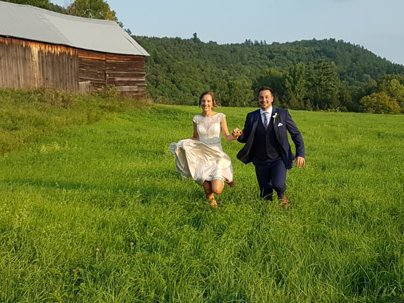 Bride and groom running hand in hand through a grassy field during a wedding photo session at The Off Grid Ark in Western Quebec, near Ottawa–Gatineau.