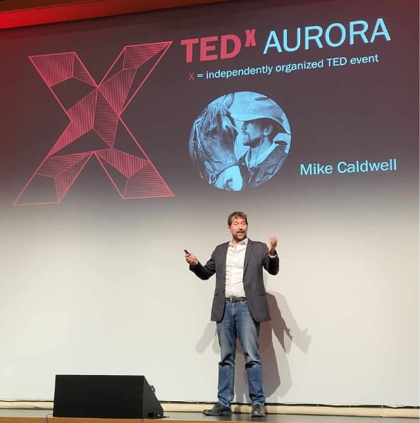 Mike Caldwell delivering a TEDx Aurora talk on stage