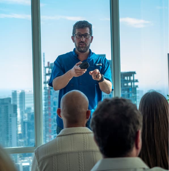 Mike Caldwell presenting to attendees at a penthouse mastermind with a city skyline in the background