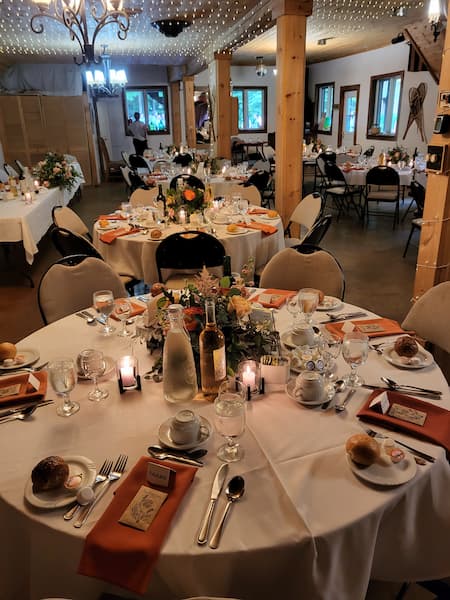 Rustic indoor wedding reception at The Ark, with decorated tables, live-edge wooden posts, and string lights.