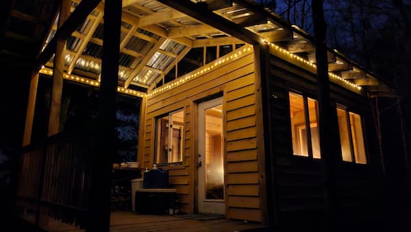 Cliffside Camp glowing with warm lights beneath its covered wooden deck at night.