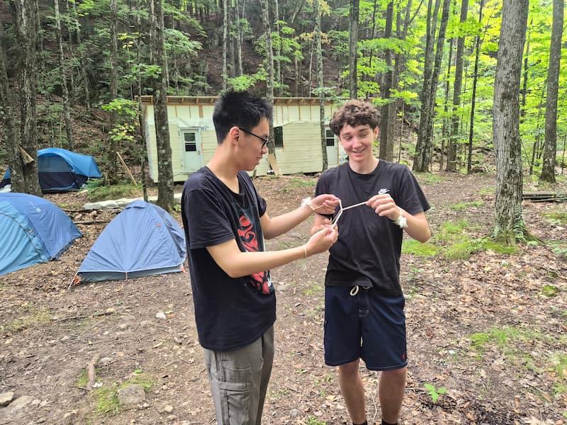 2 youth playing a rope challenge in front of the new 12'x36' indoor shelter