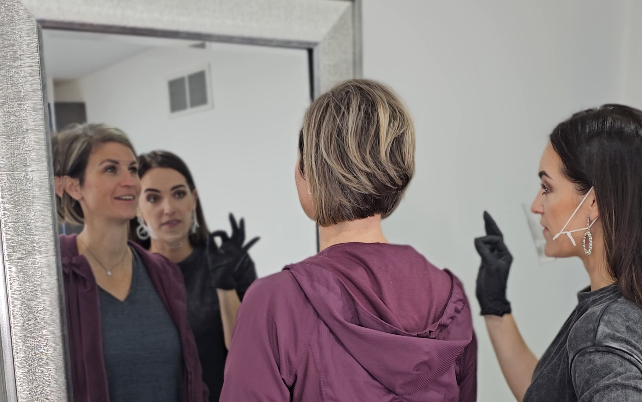 A expert laser techician giving client advice in a mirror about her skin.