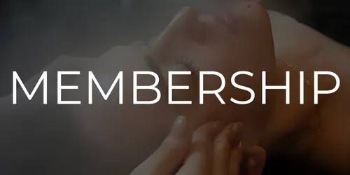 A client relaxing under a steam facial while being massaged by an esthetician.