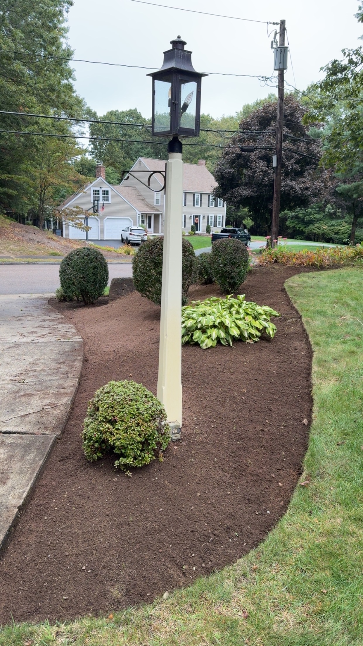 Freshly installed mulch beds and foundation plantings in a residential front yard by A. Fowkes Landscape & Construction