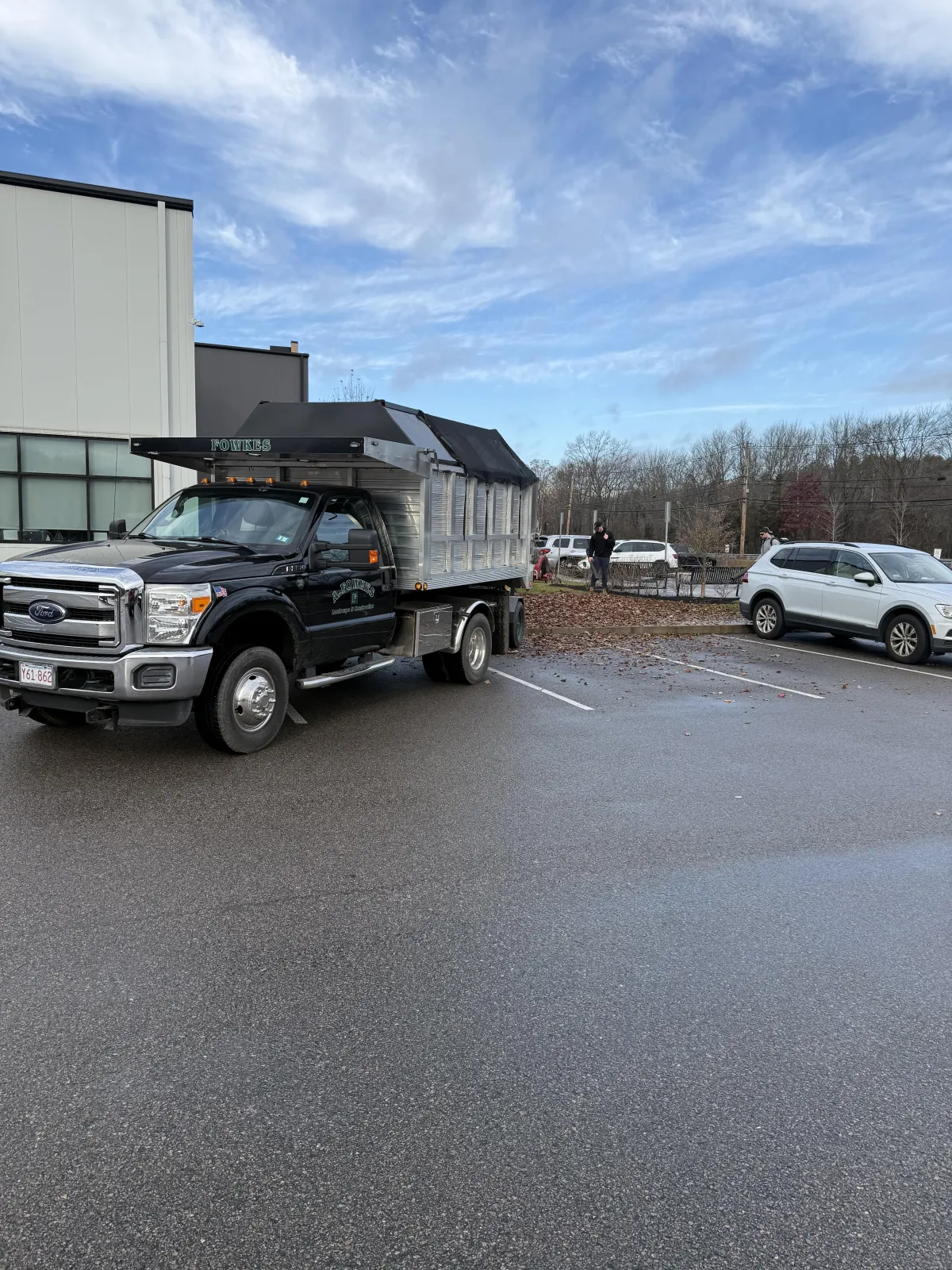 A. Fowkes Landscape & Construction truck performing fall cleanup and debris removal in a commercial parking lot