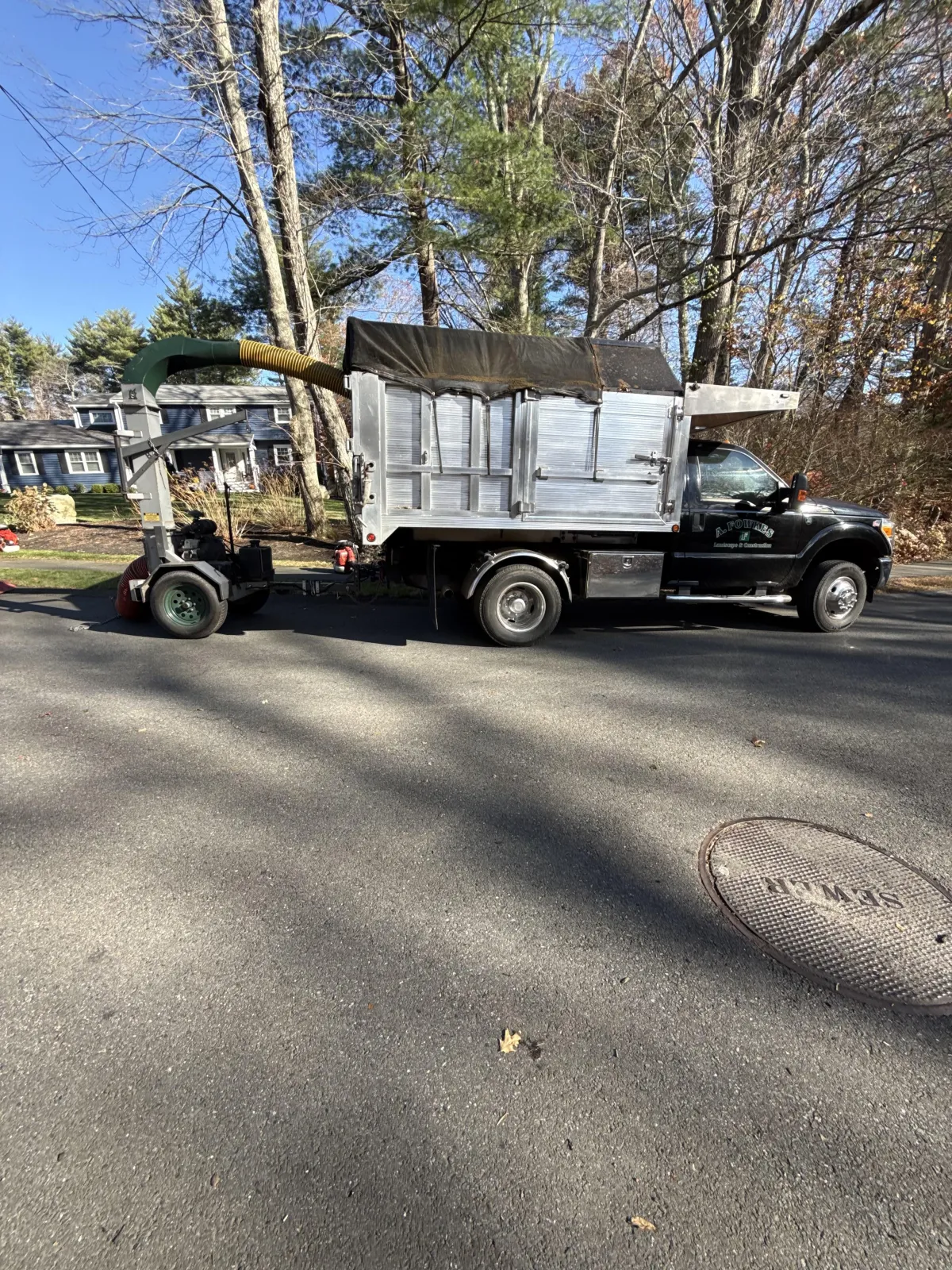 A. Fowkes Landscape & Construction truck performing residential leaf removal and seasonal yard cleanup