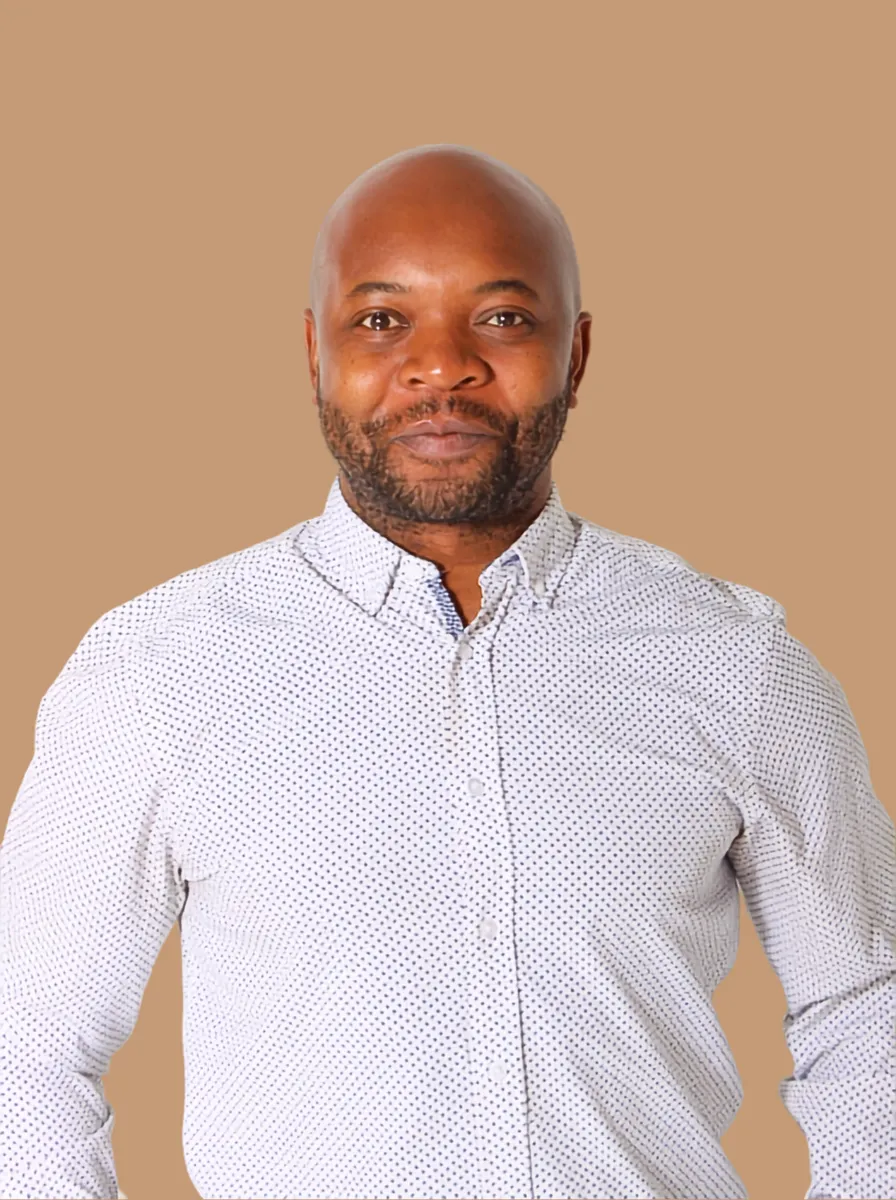 Portrait of Elias smiling in front of a warm background