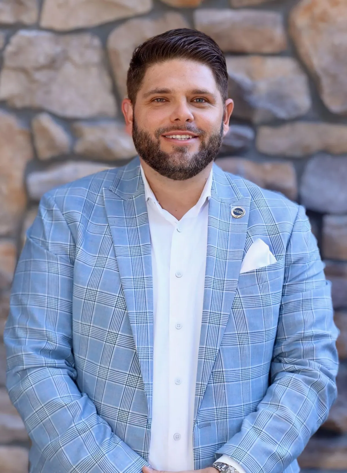Greg Sarlo, Founder and CEO, professional headshot smiling in a light blue blazer and white shirt.