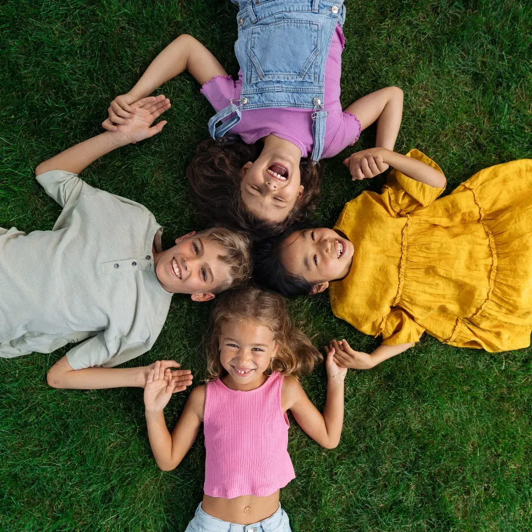 Children on ground holding hands in a circle representing community in Autism