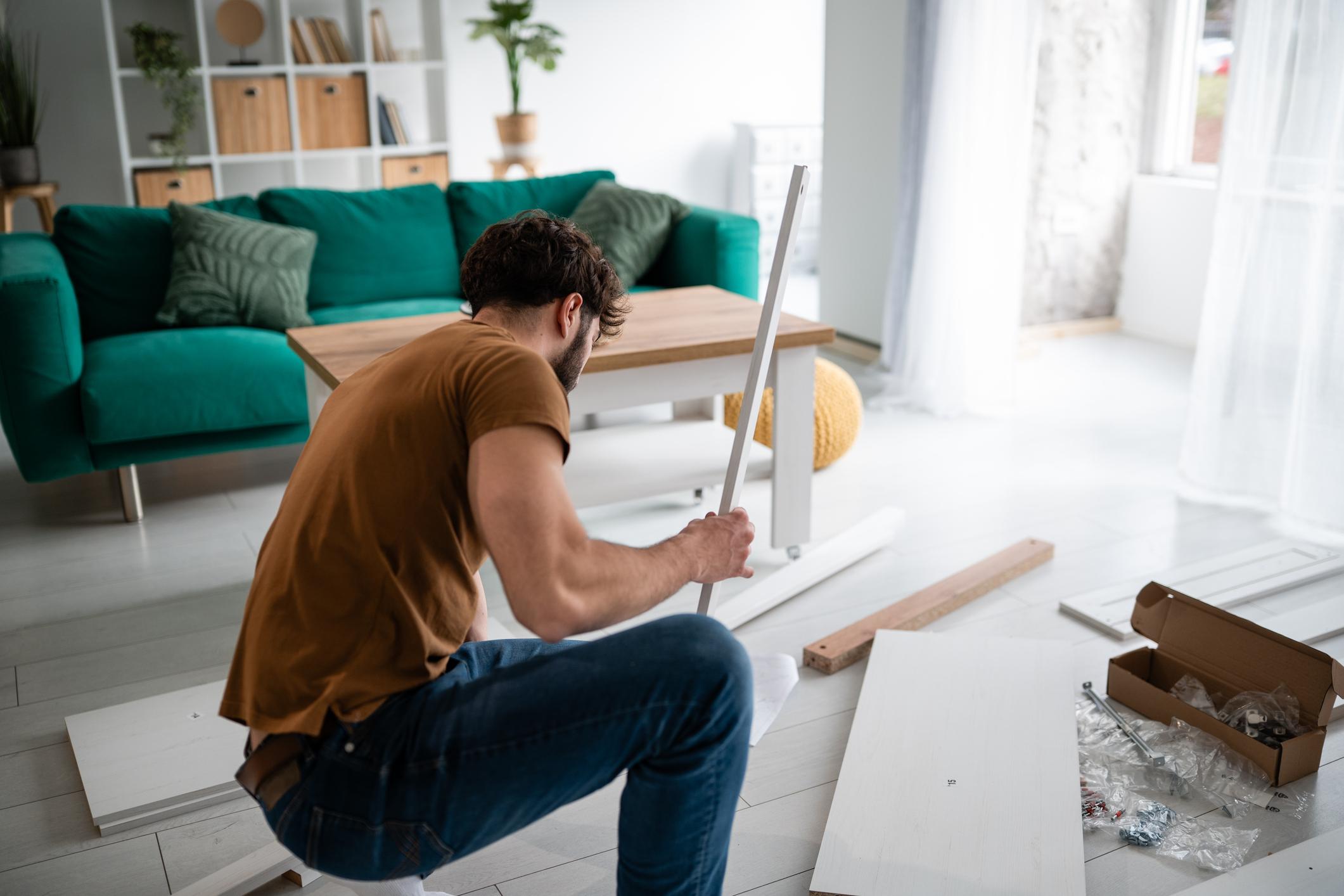 Man assembling flat-pack furniture in modern living room during home improvement project