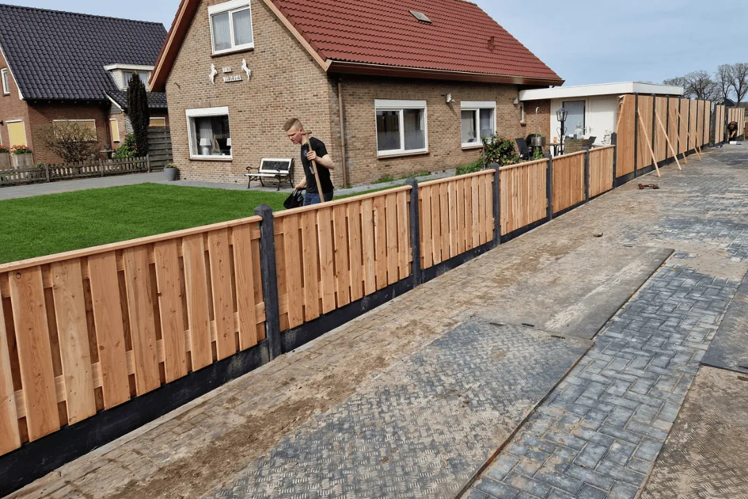 Een compleet vernieuwde schutting in de tuin. Op de foto staat ook het lachende personeel van Mulder's die de schutting hebben geplaatst. 