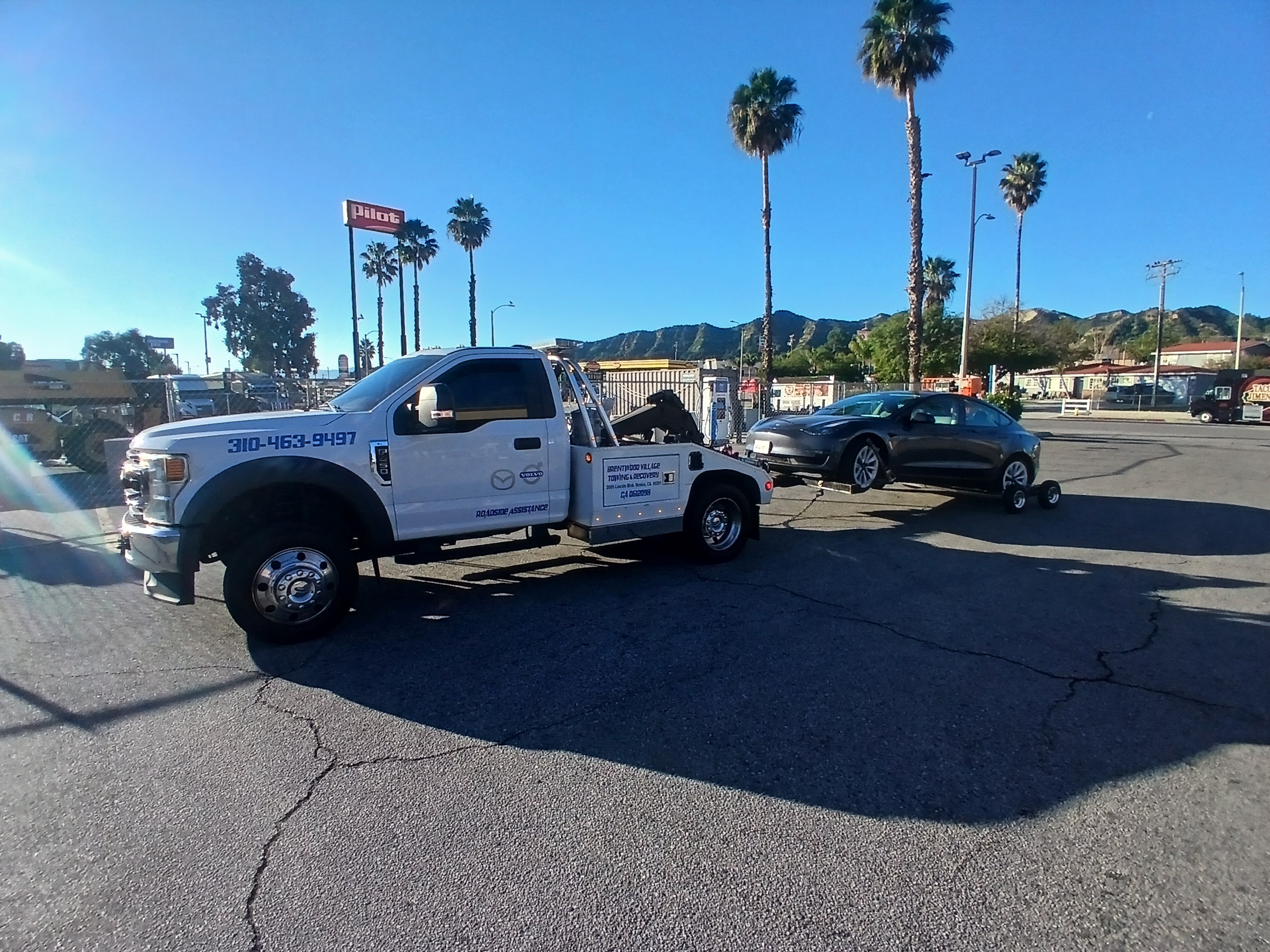 A white tow truck is parked on the street.