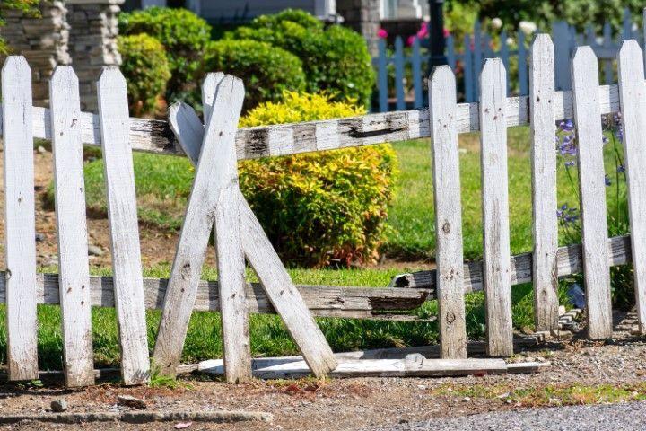 A damaged white wooden picket fence needing repair services from a professional Fencing Contractor in Galt CA.