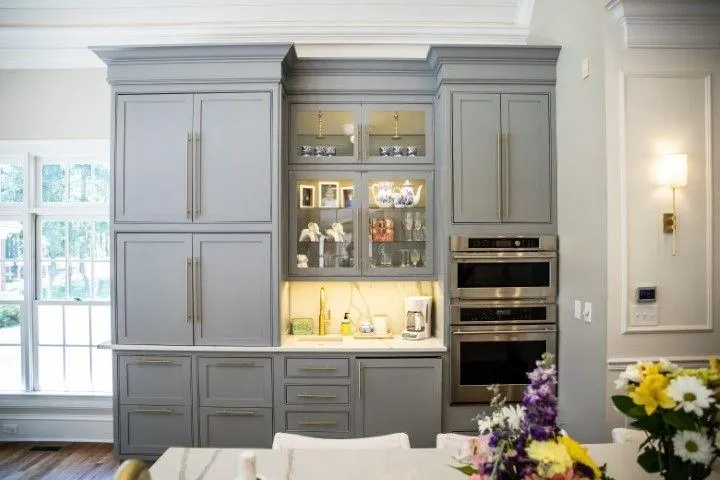 Elegant grey kitchen cabinets with brass handles and built-in appliances, custom-built by Custom Carpentry Creations.